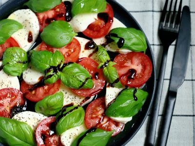 Soft focus. Classic caprese salad on a dark plate. Italian recipes concept.